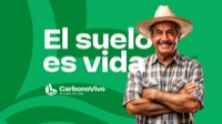 Productor sonriente junto al lema «El suelo es vida» de CarbonoVivo